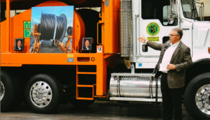 NRE speaker next to a NRE truck with pictures of Buddy Furr at a recognition ceremony.
