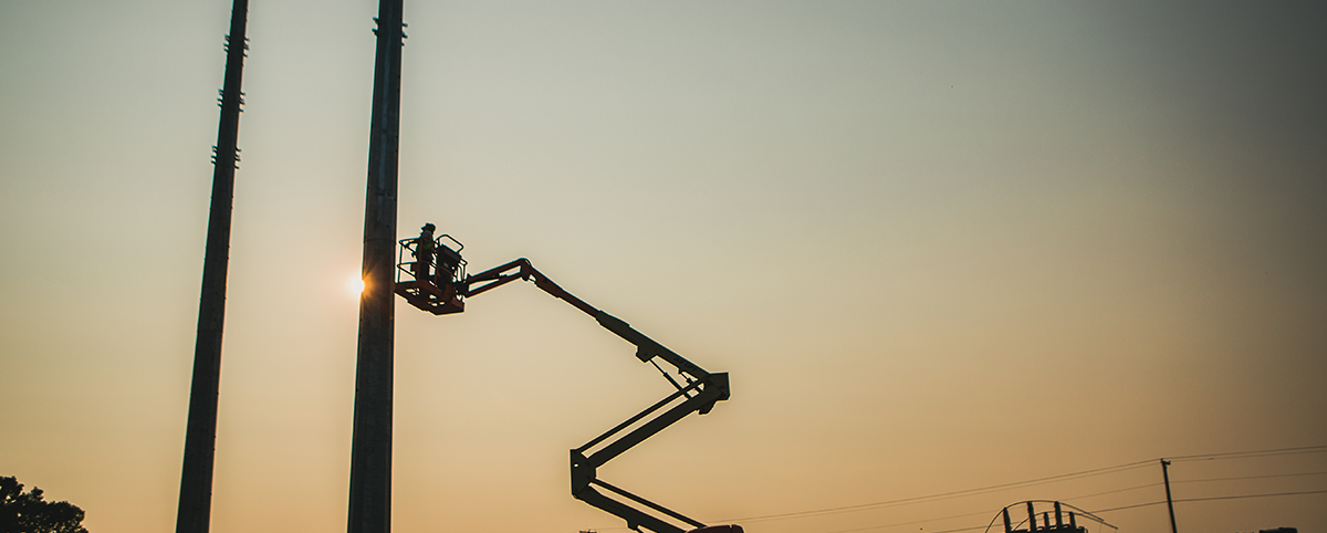 A lift with workers at a substation installation at dusk.