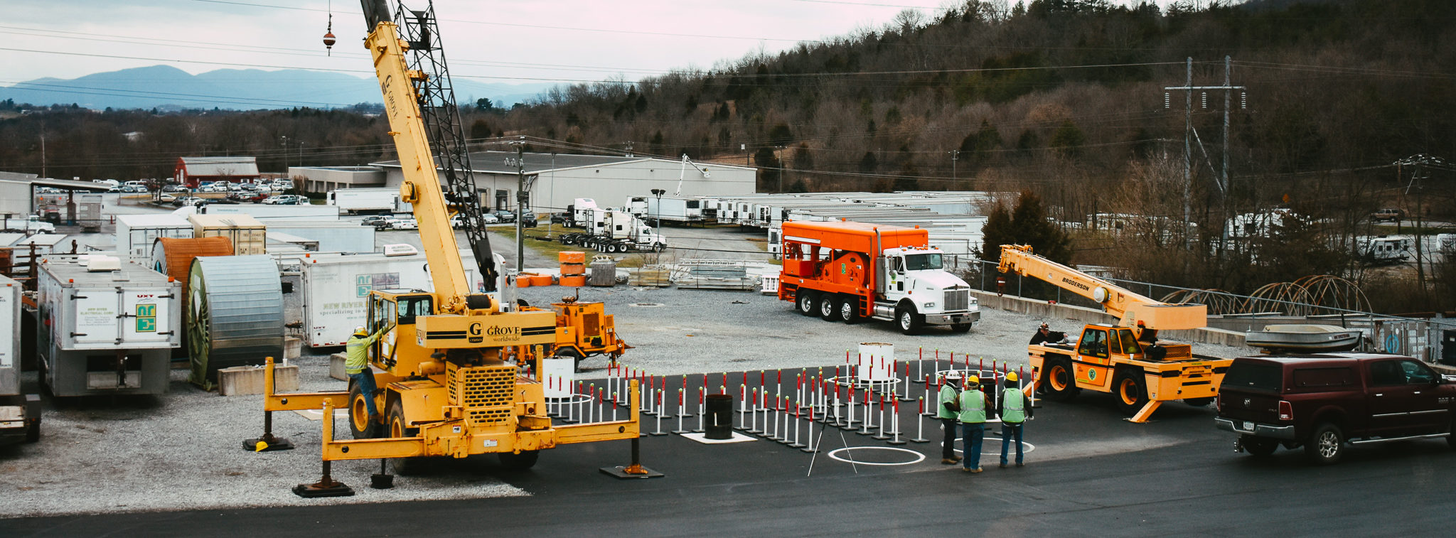 Three NRE employees at our crane exam site with two types of cranes sitting nearby.