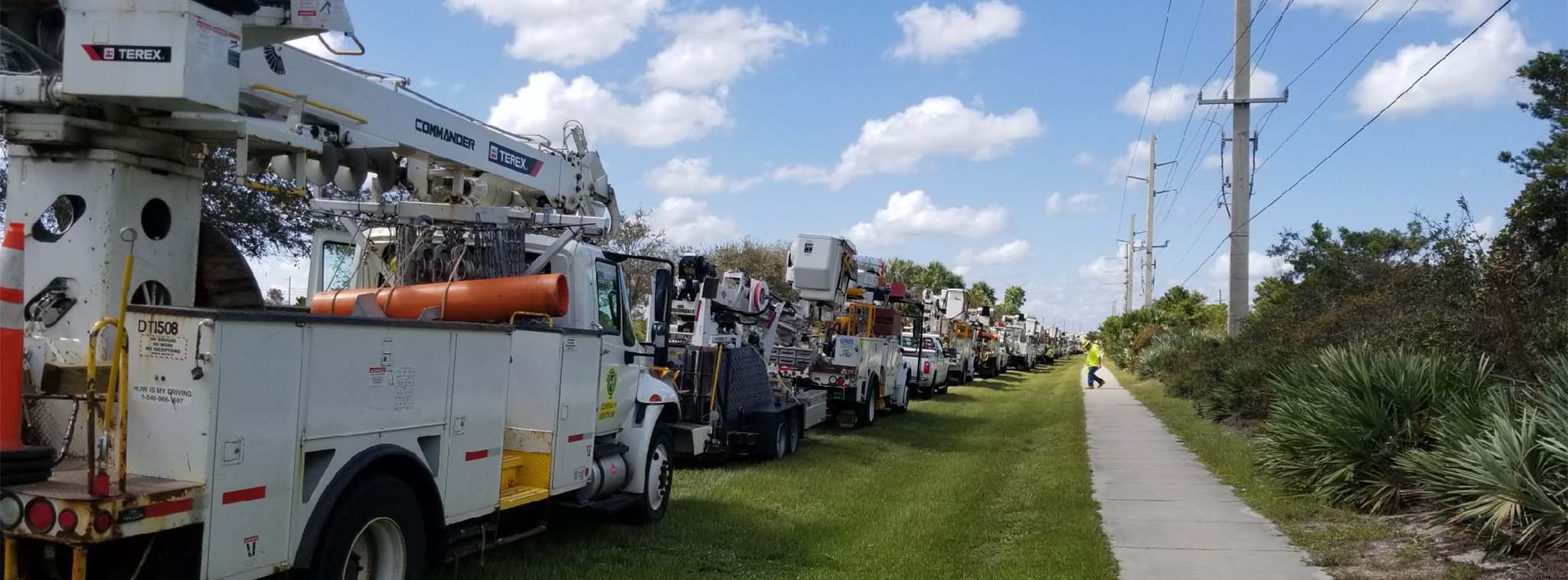 A line of New River bucket trucks waiting to restore power after a Hurricane in Florida.