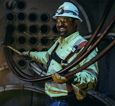 A New River Employee holding a group of cables in an underground distribution site.