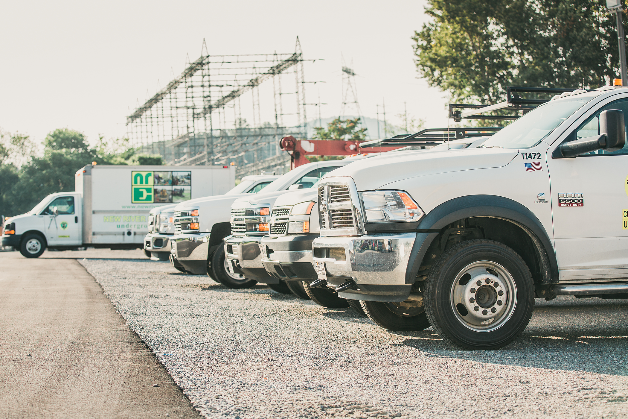 Six New River Electrical trucks lined up in front of a substation.