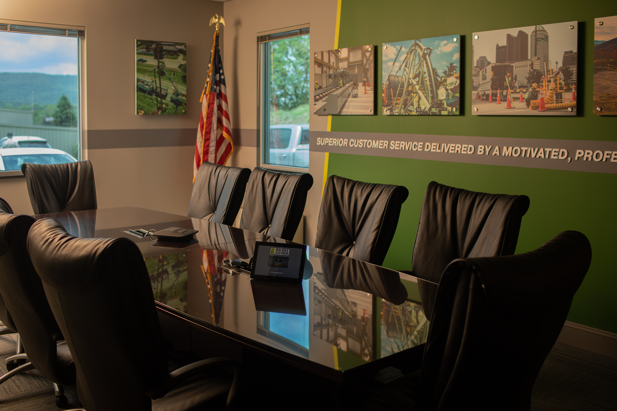 A conference room with a large table and leather chairs, an American flag, and a wall decorated with photos and a statement about customer service.