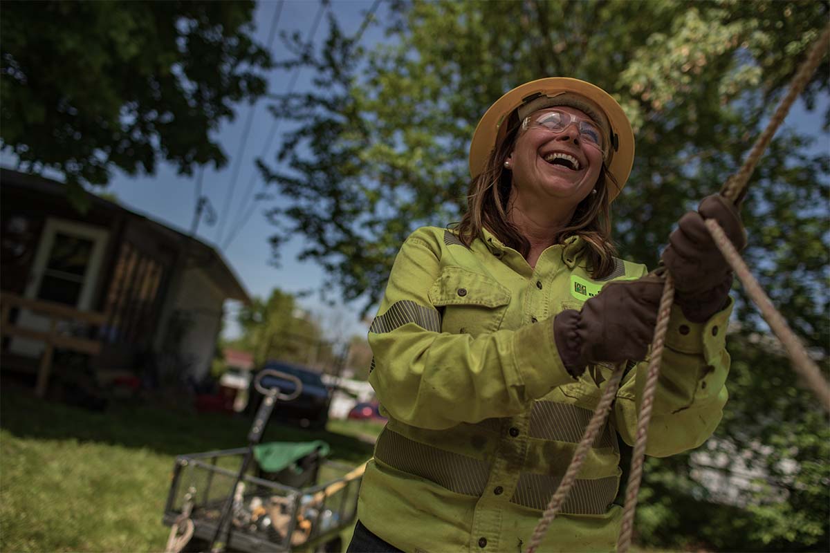A NRE women employee smiling while pulling a line on the job.