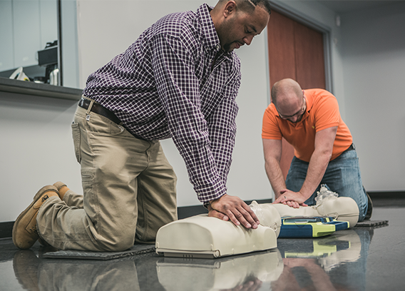 Two New River employees practicing CPR on a dummy at a safety training session.