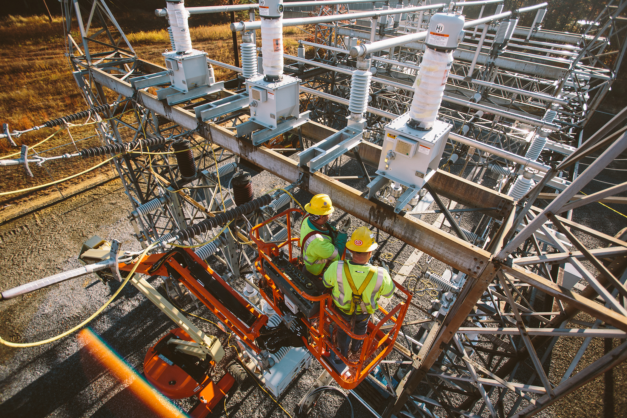 Two NRE employees in a lift working at a substation.