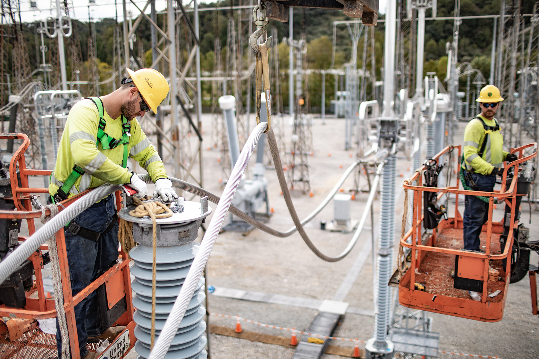 Two NRE employess working at a substation on lifts.