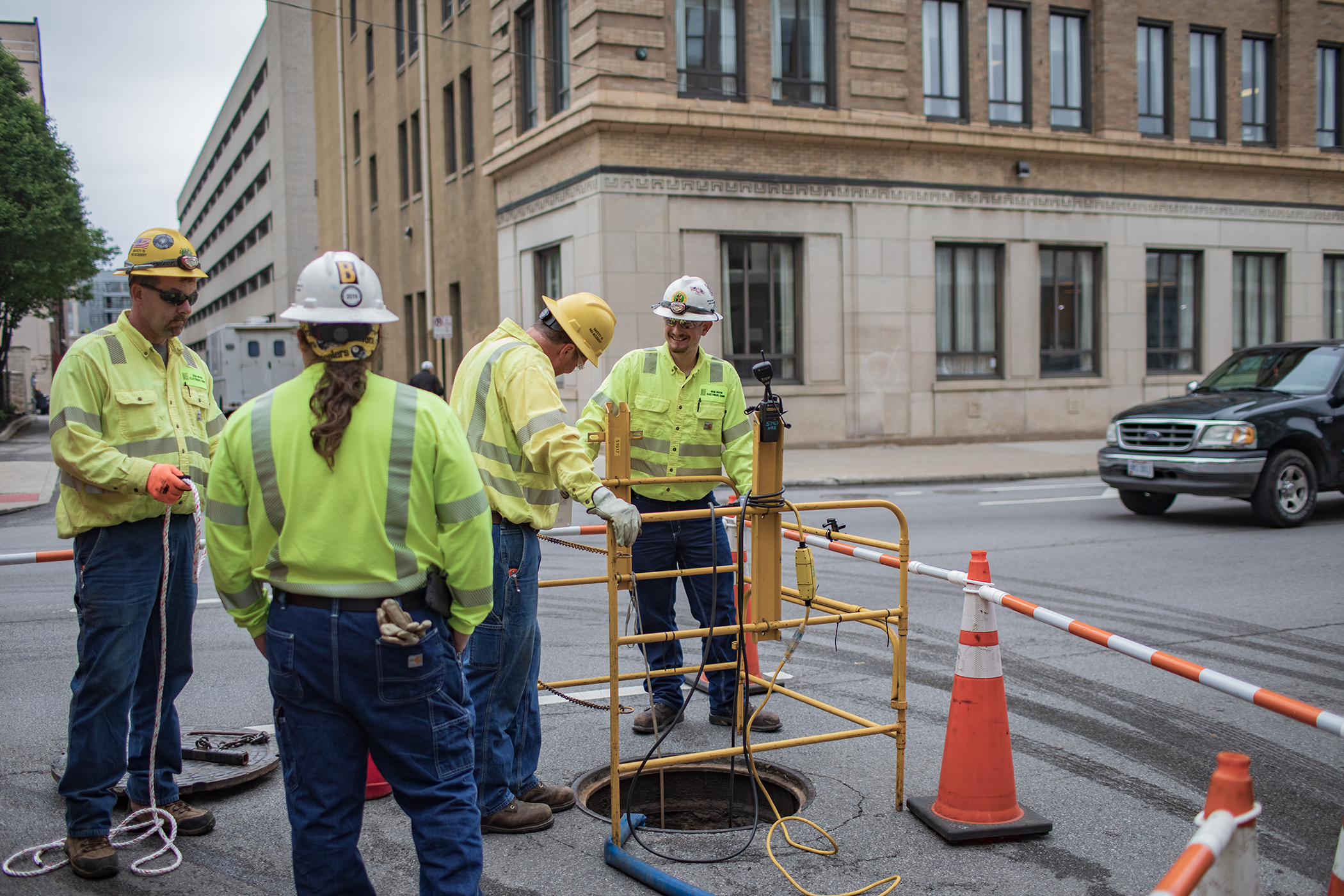 Four New River employees standing around a manhole in neon yellow personal protective equipment.