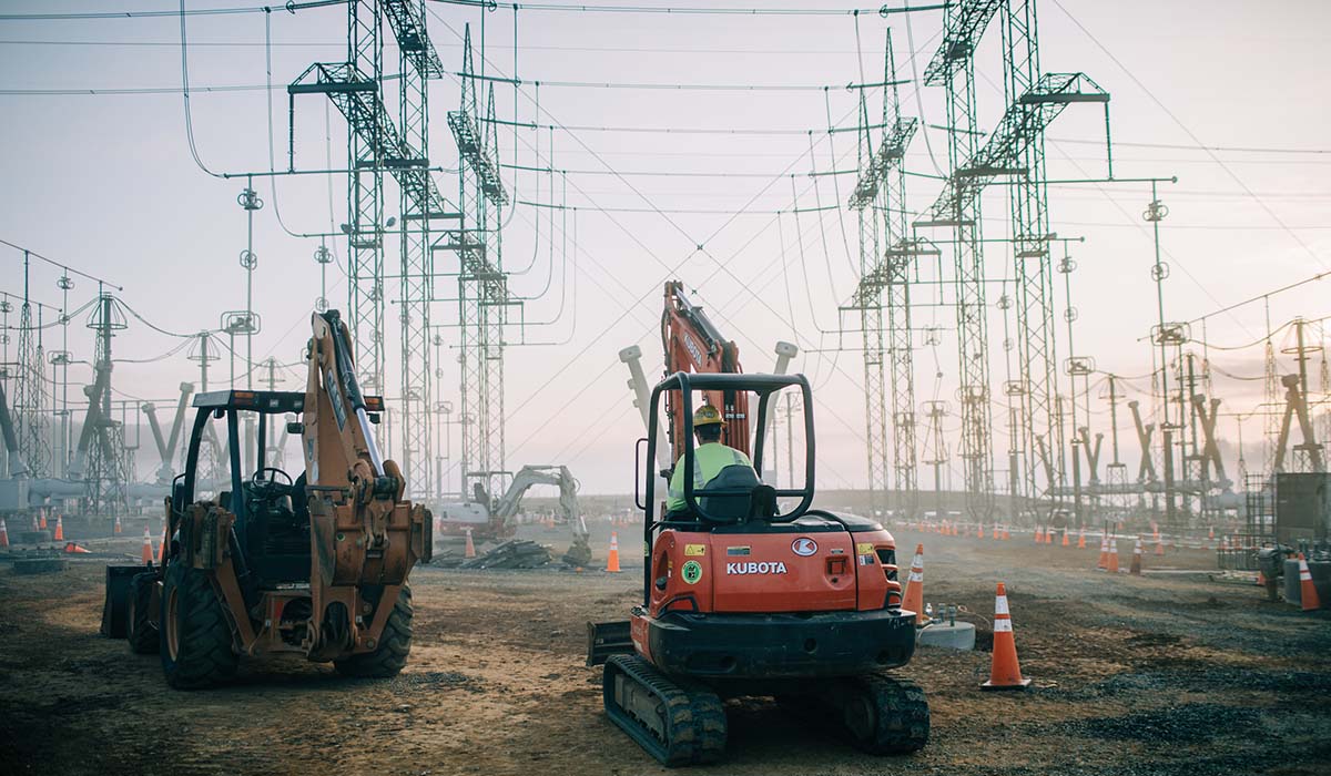 A orange backhoe sitting in front of other equipment at a substation installation in Broadford, Va.