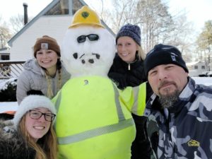Mark and his family outside with a snowman