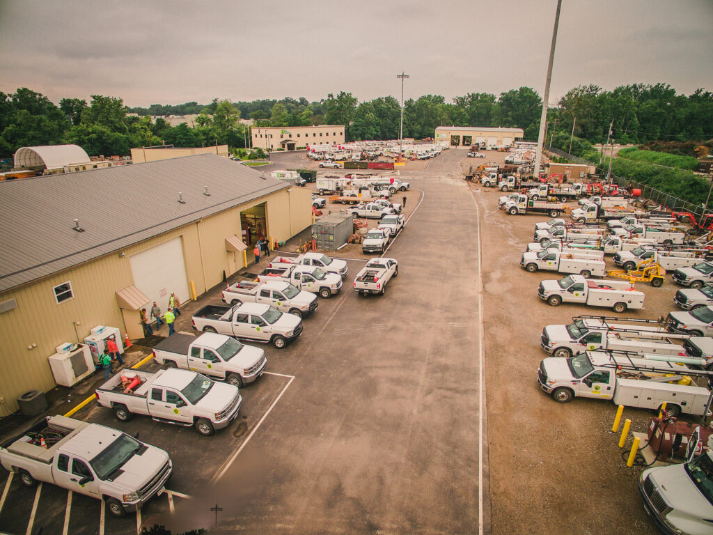 Aerial shot of NRE parking lot, filled with white work trucks and other vehicles.